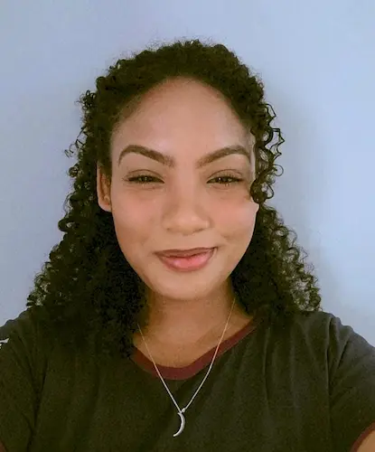 Gabrielly, artista visual e criadora da Bylin, sorrindo em seu ateliê